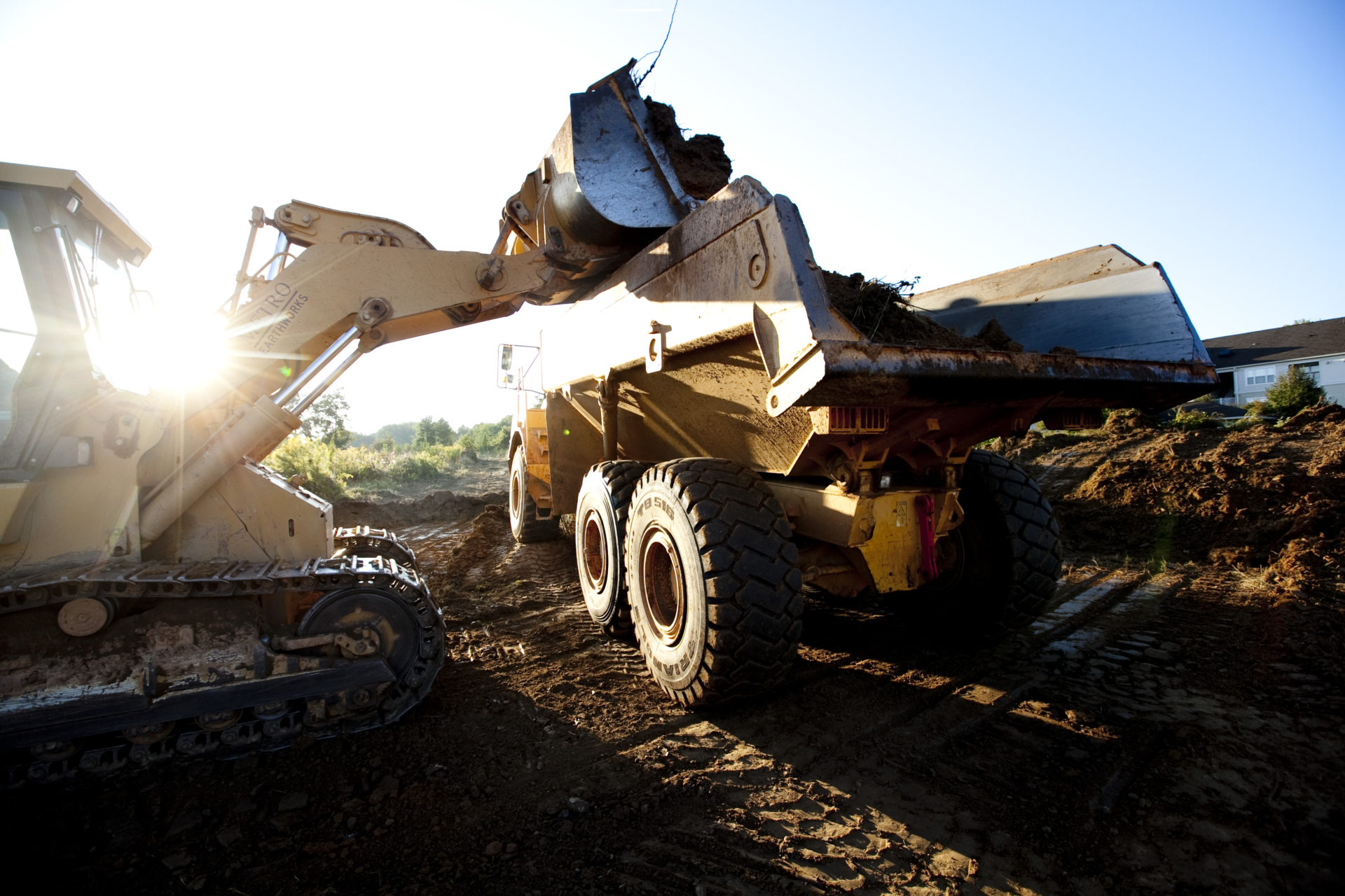 Bulldozer dumping dirt into dump truck on a jobsite